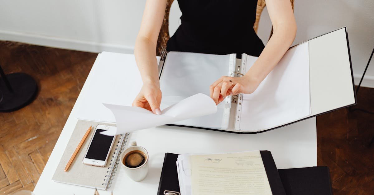 Business professional working with documents at a desk with coffee and smartphone.